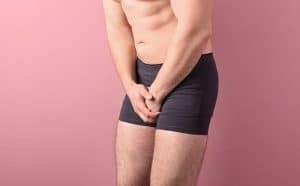 Mann in Unterhosen hält sich seinen Penis
